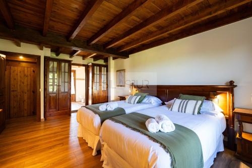 two beds in a room with wooden floors and wooden ceilings at El Balcón Del Profesor By Silastur in Cereceda