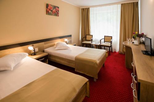 a hotel room with two beds and a window at Complex Balnear Cozia - Corp Oltul in Caciulata