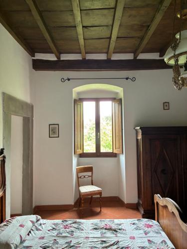 a bedroom with a bed and a chair and a window at Agriturismo Le Pozze in Dicomano