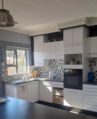 a kitchen with white cabinets and a black oven at Lee's Place in Maseru