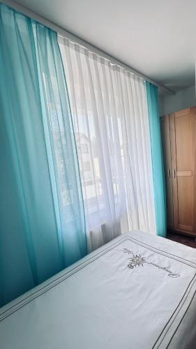 a bedroom with a bed with a blue curtain and a window at Willa Ada Pokoje & Apartamenty in Karwia