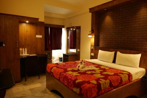 a bedroom with a bed with a dog laying on it at Sakthi Hotel in Pollāchi