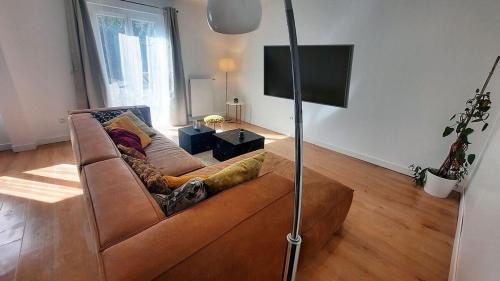 Il comprend un salon doté d'un canapé brun et d'une télévision à écran plat. dans l'établissement Maison paisible 24h du mans, à La Celle-sous-Gouzon