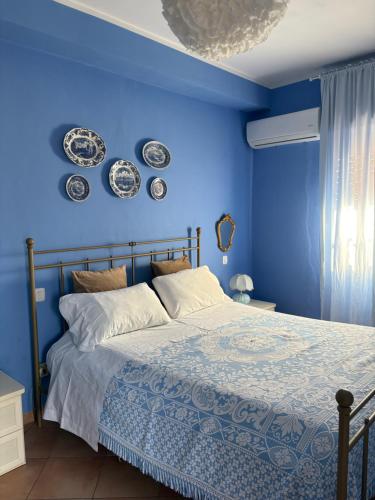 a blue bedroom with a bed and plates on the wall at FILANGERI 116 in Santa Flavia