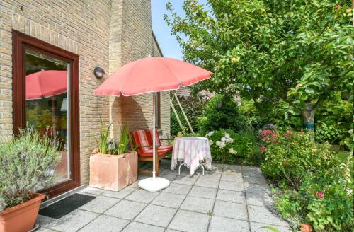 ein roter Sonnenschirm, ein Tisch und ein Stuhl in der Unterkunft Michael, Vakantiehuisje aan zee in De Haan