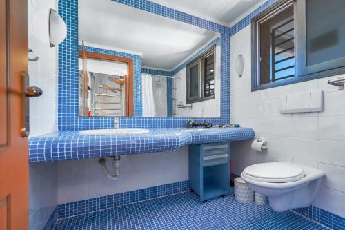 a blue and white bathroom with a toilet and a sink at Amazing view elegant Maisonette in Kriopigi