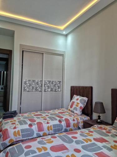 a bedroom with two beds and a headboard at Appartement - Dar Bouazza spacieux avec piscine à Dar Bouazza in Dar Bouazza
