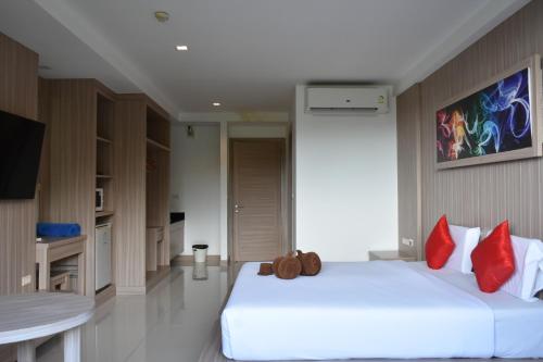 a bedroom with a large white bed with red pillows at Lae Lay Suite in Ban Karon