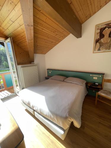 a bedroom with a large bed with a wooden ceiling at Hotel Bel Sit in Comano Terme