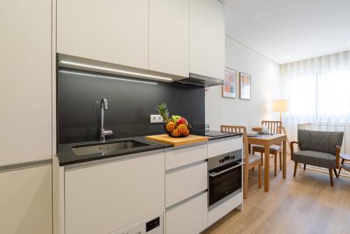 a kitchen with white cabinets and a sink and a table at HostWise - Premium & Modern Building in Porto