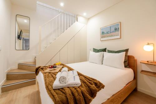 a bedroom with a bed with white sheets and a staircase at HostWise - Premium & Modern Building in Porto