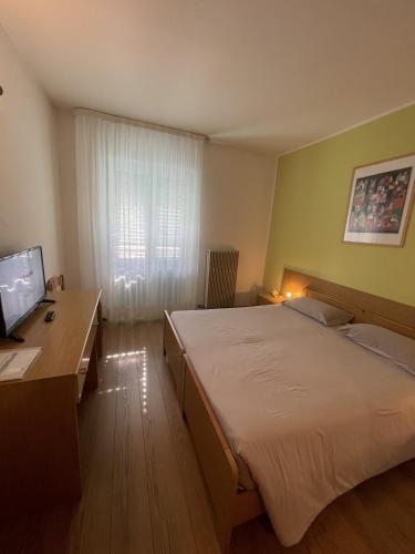 a bedroom with a bed and a desk and a television at Hotel Bel Sit in Comano Terme