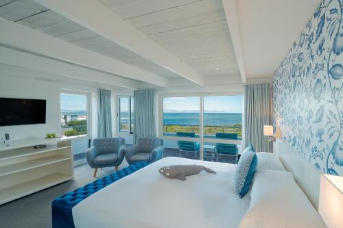 a bedroom with a large white bed and a television at One Marine Drive Boutique Hotel & Spa by The Living Journey Collection in Hermanus