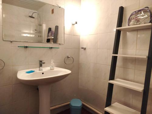 La salle de bains est pourvue d'un lavabo, d'un miroir et d'étagères. dans l'établissement Proche du port beau T3 lumineux tout confort avec parking - 4RS121, à Saint-Cyprien