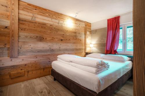 two beds in a room with wooden walls at LAltro John in Folgaria