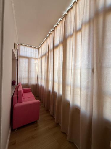 a pink couch in front of a window with curtains at classy apartment Lea 3 in Durrës