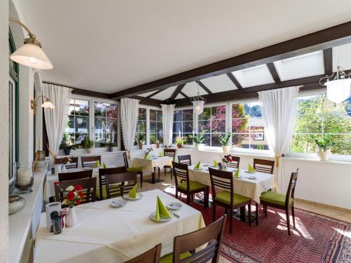 a restaurant with white tables and chairs and windows at Landhaus Maximilian in Hopfgarten im Brixental