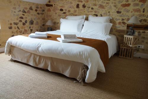 une chambre avec un grand lit avec des draps et des oreillers blancs dans l'établissement Le Moulin Des Fumades, à Payrignac