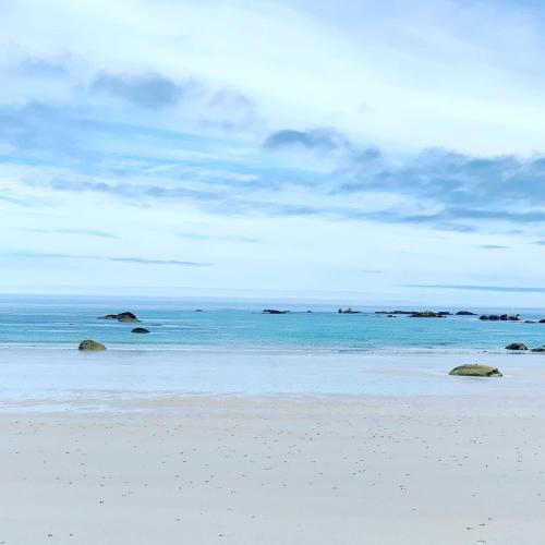a beach with rocks in the ocean under a cloudy sky at Ty Marie Neiz Vran - Villa luxe vue mer, 80 mètres de la plage in Kerlouan