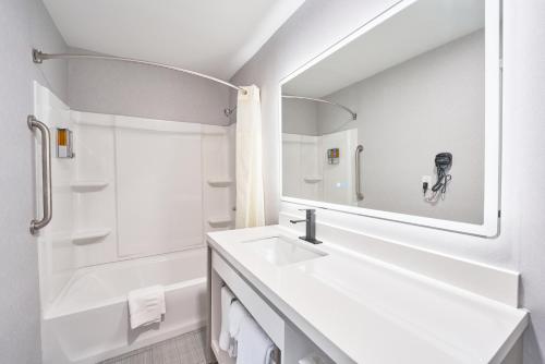 a white bathroom with a sink and a mirror at All Seasons Inn & Suites in Bourne