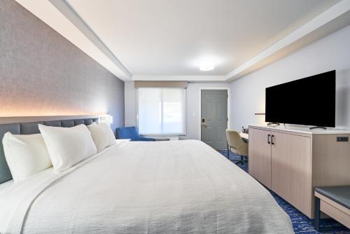 a hotel room with a large bed and a flat screen tv at All Seasons Inn & Suites in Bourne