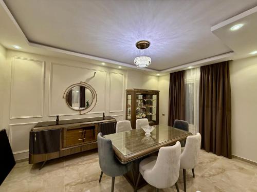 a dining room with a table and chairs and a mirror at House in 6th Of October