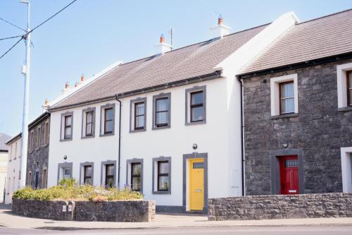 a white building with a red door on a street at 3 bedroom Townhouse in the heart of the Burren in Ballyvaughan