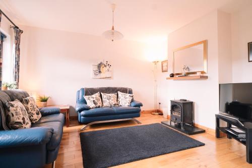 a living room with two blue couches and a television at 3 bedroom Townhouse in the heart of the Burren in Ballyvaughan