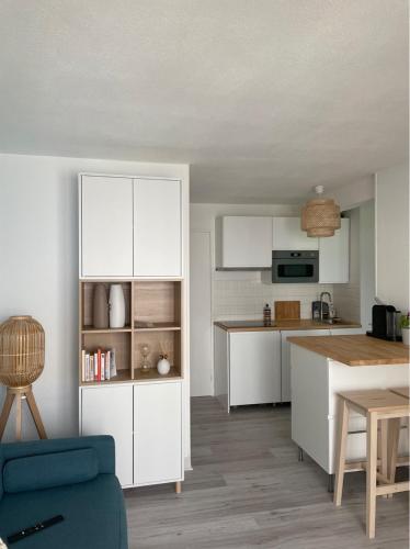 une cuisine avec des placards blancs et un canapé bleu dans l'établissement Appartement rénové avec piscine, plage 2mns à pied, au Cap d'Agde