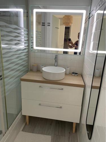 une salle de bain avec un lavabo et un miroir dans l'établissement Appartement rénové avec piscine, plage 2mns à pied, au Cap d'Agde
