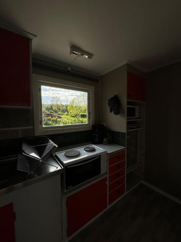 a small kitchen with a stove and a window at Bäckagården - self catering - självhushåll in Skövde