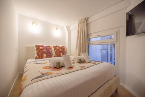 une chambre blanche avec un grand lit avec une fenêtre dans l'établissement CIA - Cozy Flat Palais Royal, Louvre, à Paris