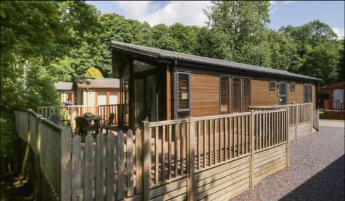 a wooden cabin with a fence in front of it at Brook Lodge in Troutbeck Bridge