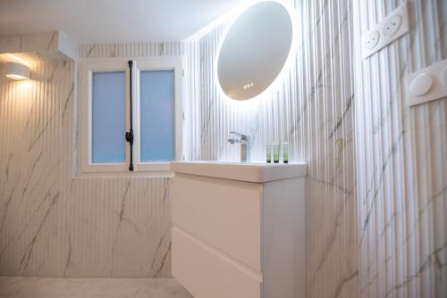 une salle de bain blanche avec un lavabo et un miroir dans l'établissement CIA - Cozy Flat Palais Royal, Louvre, à Paris