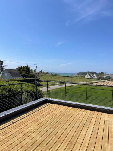 a wooden deck with a view of a field at Ty Marie Neiz Vran - Villa luxe vue mer, 80 mètres de la plage in Kerlouan