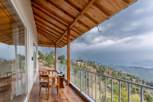 a room with a balcony with a table and chairs at Shree Parijat Resort - Luxury Resort in Mukteshwar in Mukteswar