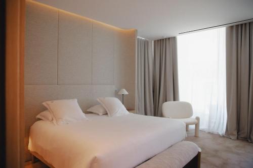 a bedroom with a large white bed and a chair at Domaine de Verchant & Spa - Relais & Châteaux in Montpellier