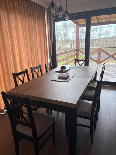 a dining room table with chairs and a large window at Dom na Skarpie in Małdyty