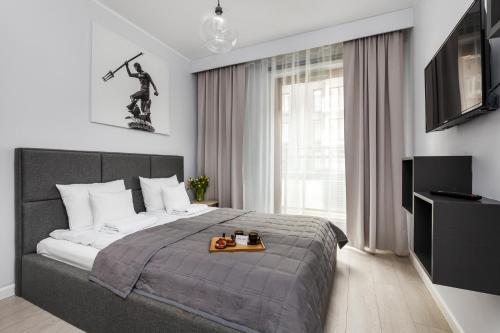 a bedroom with a bed with a tray of food on it at Nowa Motława Residence by HappyStay in Gdańsk