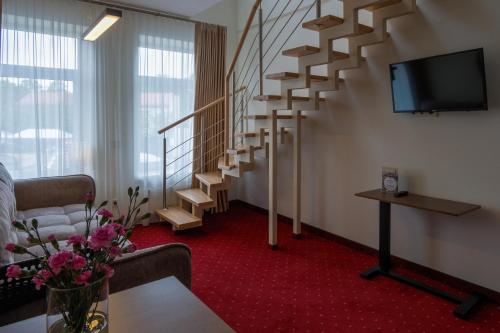 a hotel room with a staircase and a tv at Agneta Apartamentai in Druskininkai