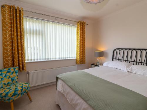 a bedroom with a bed and a chair and a window at Hillside in Cheltenham