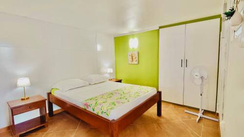 a bedroom with a bed and a green wall at Tierra Verde, la nature à 15 min de Fort-de-France in Saint-Joseph
