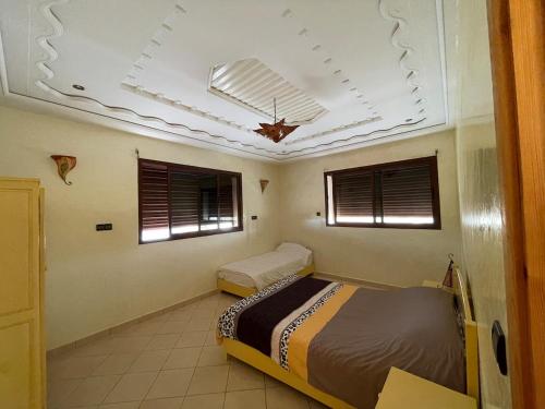a bedroom with a bed and two windows and a ceiling at Modern villa with pool in Mirleft