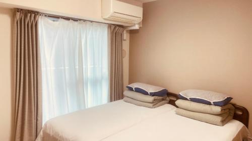 a bedroom with two beds with pillows and a window at SkyHotel Ryogoku 駅徒歩4分 in Tokyo