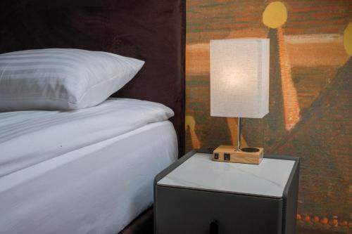 a lamp on a night stand next to a bed at Agneta Apartamentai in Druskininkai