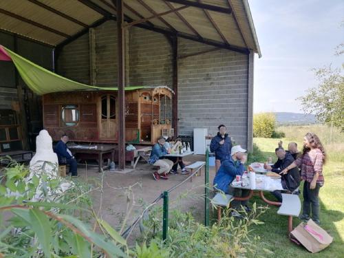 un groupe de personnes assises à des tables dans un pavillon dans l'établissement Les Arts En Ciel, à Neuvy-Grandchamp