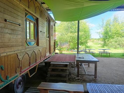 une table de pique-nique et un wagon avec un parapluie dans l'établissement Les Arts En Ciel, à Neuvy-Grandchamp