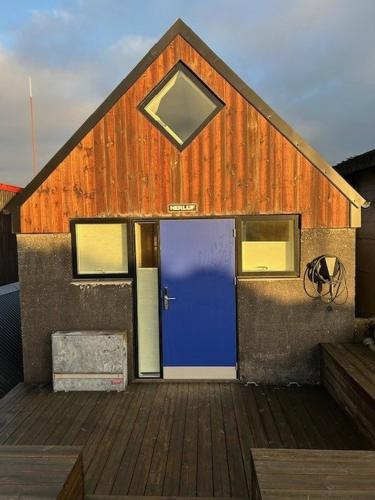 a building with a blue door on a wooden deck at Charming Apartment in Strendur Faroe Islands, with Stunning Seaview in Strendur
