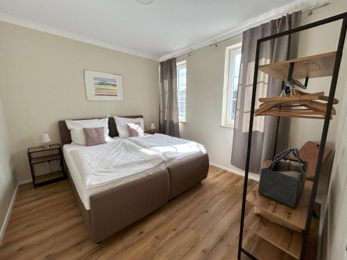 a bedroom with a bed with white sheets and wooden floors at Feriendomizil im Saarschleifenland in Mettlach