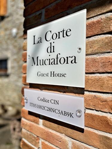 a sign for a guest house on a brick wall at Corte di Muciafora Living in Borgo a Giovi